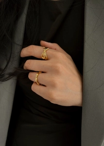 Close-up of golden bamboo shaped ring and intertwined knot ring on model's hand
