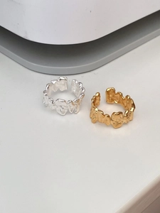 Macro shot of irregular textured silver and gold adjustable rings with lava-like surface