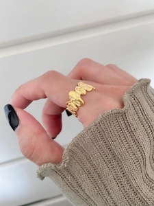 Detailed view of wide gold irregular textured ring on model with brown sweater