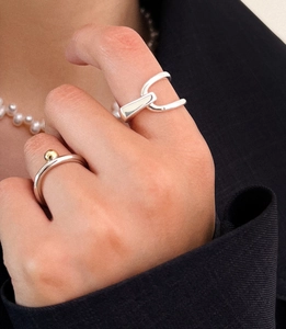 Detail of minimalist geometric 925 silver rings worn with black suit and pearl necklace