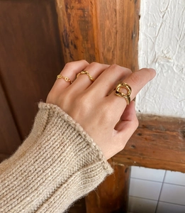 Detail of gold geometric hollow open rings on hand with warm knitwear and vintage background
