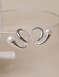 Detailed macro view of S925 sterling silver curved earrings with elegant white pearls