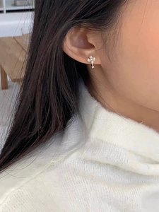 Gros plan de boucles d'oreilles trèfle en argent sterling S925 portées sur l'oreille