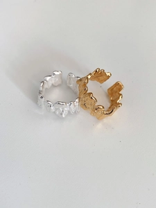 Close-up of irregular lava texture design on adjustable silver and gold open rings