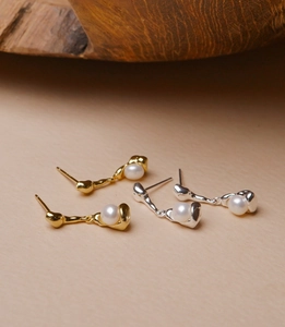 Detailed view of 925 silver pearl drop earrings in gold and silver metallic finishes