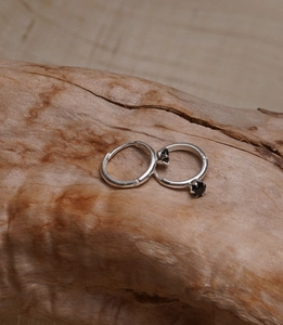 Macro shot of a 925 sterling silver hoop earring with a black star-shaped gemstone detail