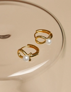 Detail of 925 sterling silver gold hoop earring with white pearl and bow knot design