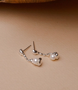 Detail view of 925 silver fluid design earrings with elegant round white pearls