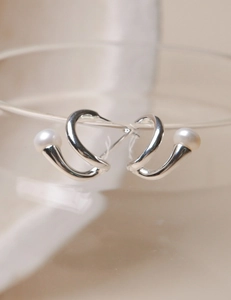 Detailed macro view of S925 silver U-shape spiral earrings with white freshwater pearls