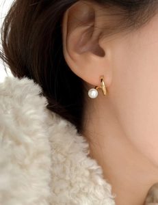 Close-up of minimalist 925 silver pearl stud earring worn on model with soft lighting