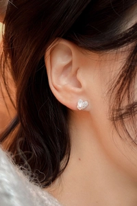 Detail of heart-shaped pearl stud earring with crystal halo on female model ear