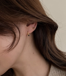 Close-up of minimalist gold mini earrings with black stone studs on female model ear