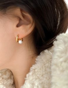 Close-up of minimalist gold twisted C-shape earring with a white pearl on a model