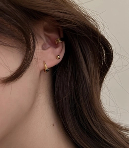 Close-up of gold ear cuff, ball stud, and black stone hoop earring set on ear