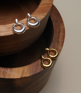 Macro shot of gold and silver irregular donut earrings on a wooden bowl display