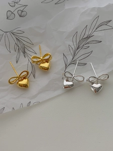 Gros plan de boucles d'oreilles cœur et nœud en or et argent avec finition miroir polie