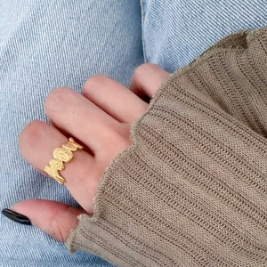 Irregular textured wide gold lava ring shown on hand with knitted sleeve background
