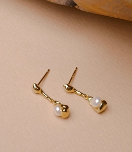 Detail of elegant gold-plated irregular geometric earrings with lustrous white pearls