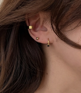 Close-up of minimalist gold ear cuff and small stud earring set on a female ear