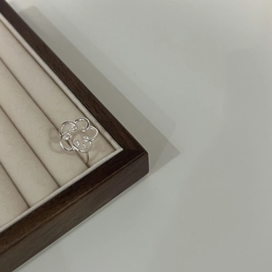 Detail of 925 sterling silver hollow flower ring displayed in a beige jewelry box