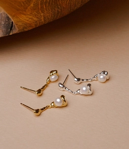 Macro detail of irregular gold and silver pearl stud earrings with minimalist design