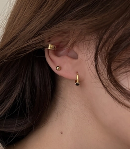 Close-up of gold ear cuff and ball stud set with a black gemstone drop earring
