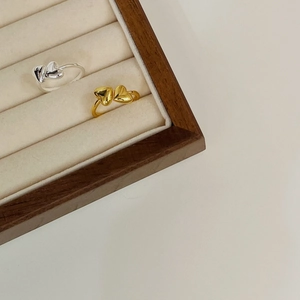 Detailed view of silver and gold interlaced heart rings in a velvet jewelry box display