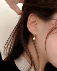 Close-up of elegant gold drop earrings with lustrous white pearls on female model