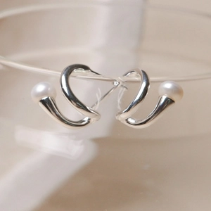 925 silver twist stud earrings with round white pearls on a glass rim closeup
