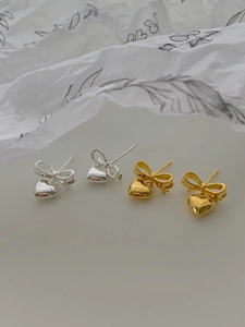 Détails de boucles d'oreilles nœud et cœur en argent et or sur fond esthétique