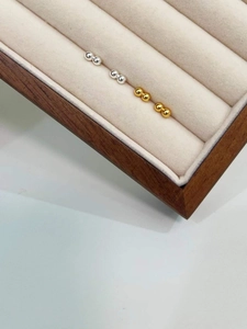 Macro detail of high-polish silver bean stud earrings on a velvet jewelry display tray