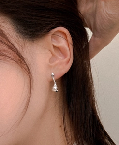 Detailed view of silver irregular curved pearl earrings on a female model