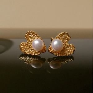 Elegant gold heart earrings with freshwater pearls on a reflective black surface