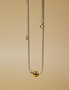 Detail view of gold and silver polished beads on a sparkling minimalist snake chain necklace