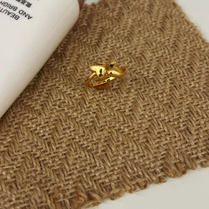 Detail view of gold double heart-shaped open ring on rustic linen fabric background