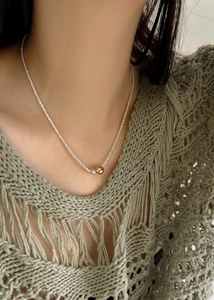 Close-up of gold and silver sphere charms on a sparkling ice chain necklace for women