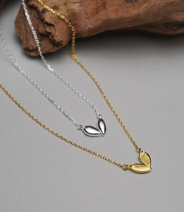 Detailed view of polished V-shaped and double-leaf pendants in gold and silver finish