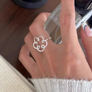 Minimalist 925 sterling silver hollow flower open ring on a female hand in soft light