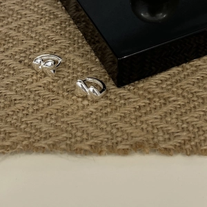 Macro shot of 925 sterling silver heart-shaped huggie earrings on a textured display