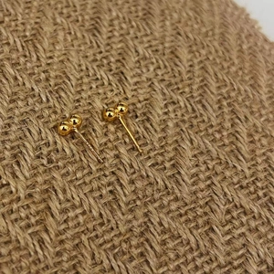 Minimalist 925 sterling silver bean stud earrings in gold finish on rustic fabric