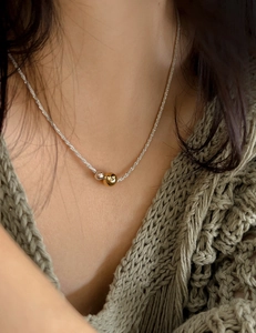 Close-up of dual gold and silver bead pendant necklace on a knitted sweater