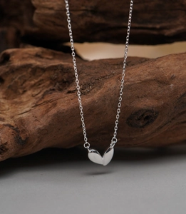 Macro shot of 925 sterling silver heart pendant necklace on natural wood background