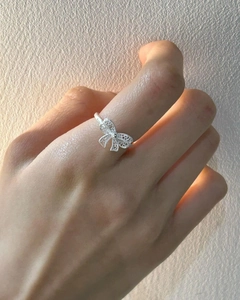 Detail of 925 sterling silver hollow bow ring shown on a finger with soft lighting