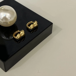 Elegant gold heart-shaped hoop huggie earrings presented on a sleek black display