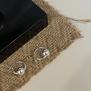 Close-up of minimalist 925 sterling silver hoop earrings with smooth solid sphere charms