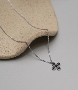 Close-up of a 925 silver necklace with a black zircon clover cross pendant on ceramic