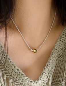 Detail of minimalist mixed metal bead necklace on model with silver and gold spheres