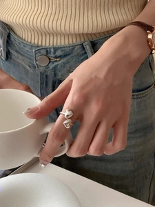 Detailed close-up of 925 sterling silver heart ring worn while holding a white ceramic cup