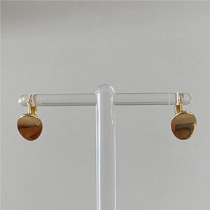 Détail de boucles d'oreilles dorées avec pendentifs disques irréguliers sur support