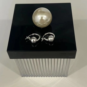 Detail view of 925 sterling silver hoop earrings with polished ball charms on a black base